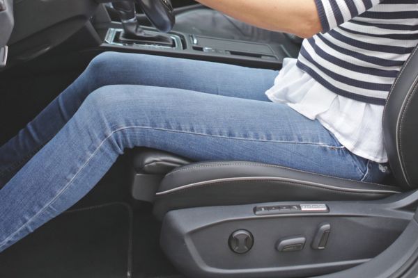 Nahaufnahme der Sitzfläche und Beine einer Person auf dem Fahrersitz zur Einstellung einer ergonomischen Sitzposition.