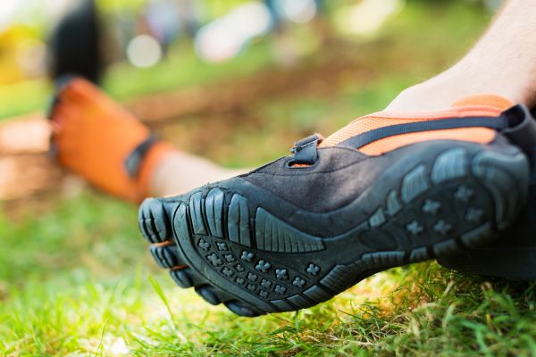 Nahaufnahme von Füßen in Barfußschuhen auf einer Wiese im Freien.