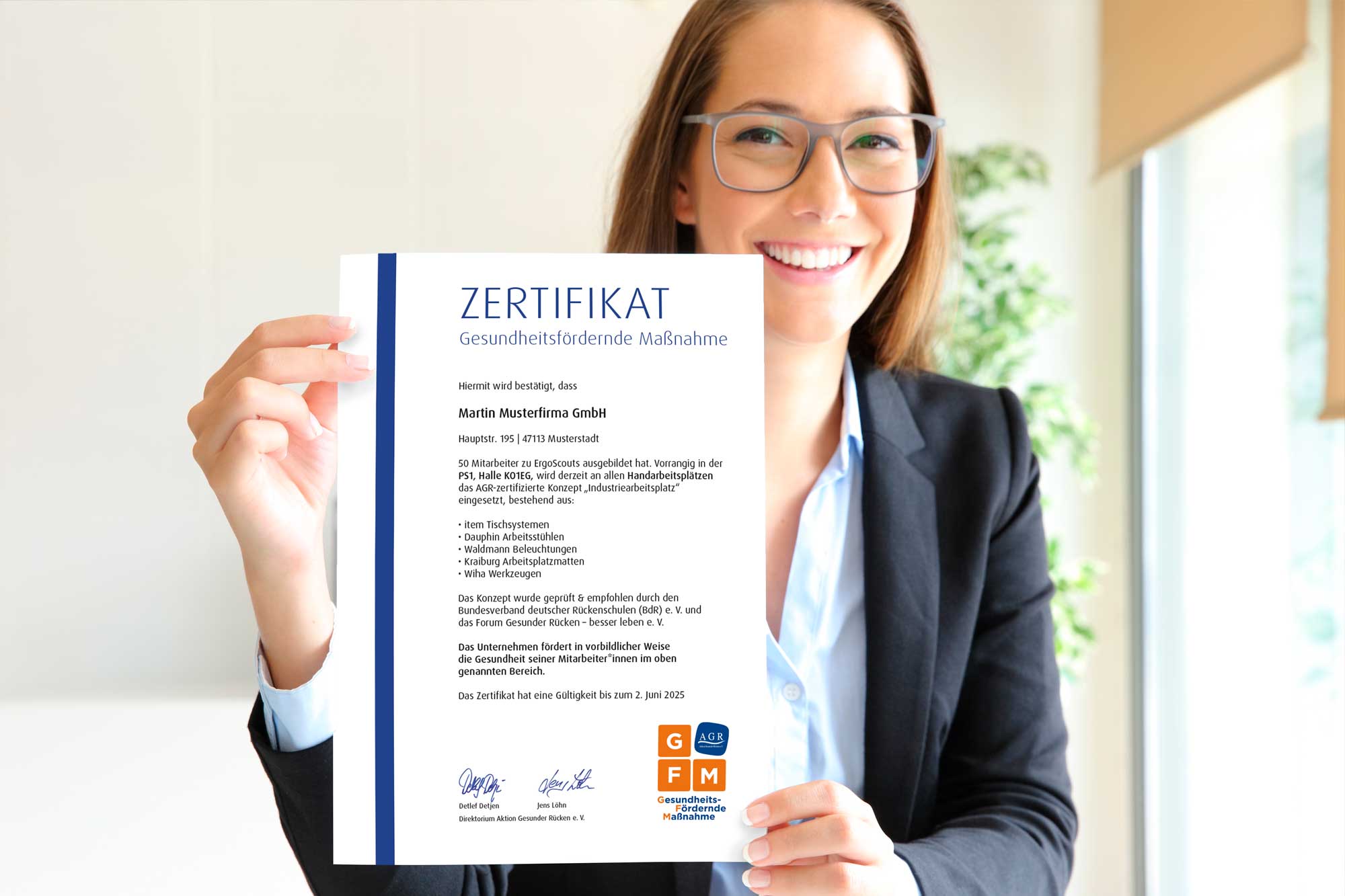 eine Frau hält die Urkunde zur GFM in die Kamera und lächelt dabei.