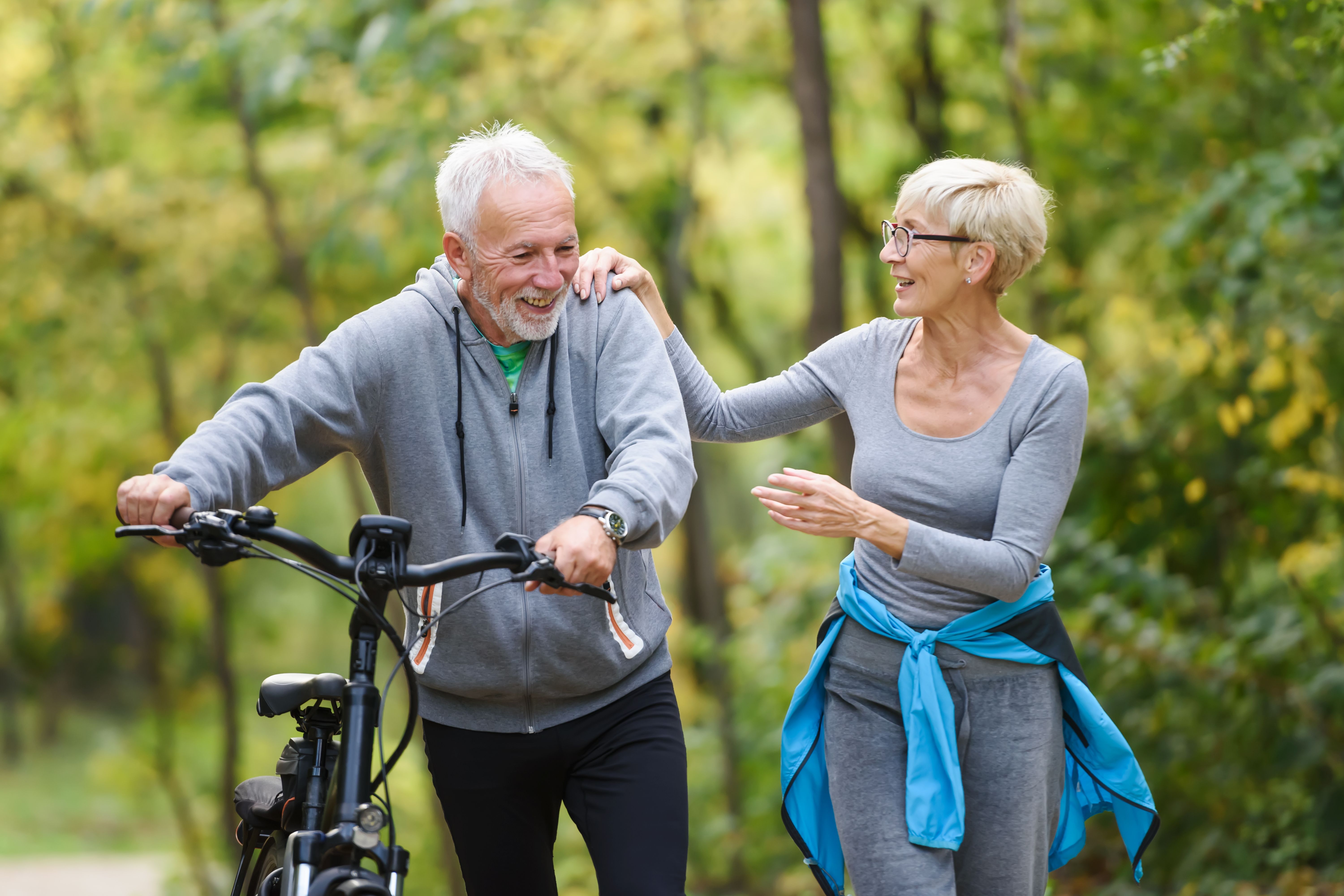 Ein älterer Mann mit Fahrrad und eine Frau beim Sport im Wald