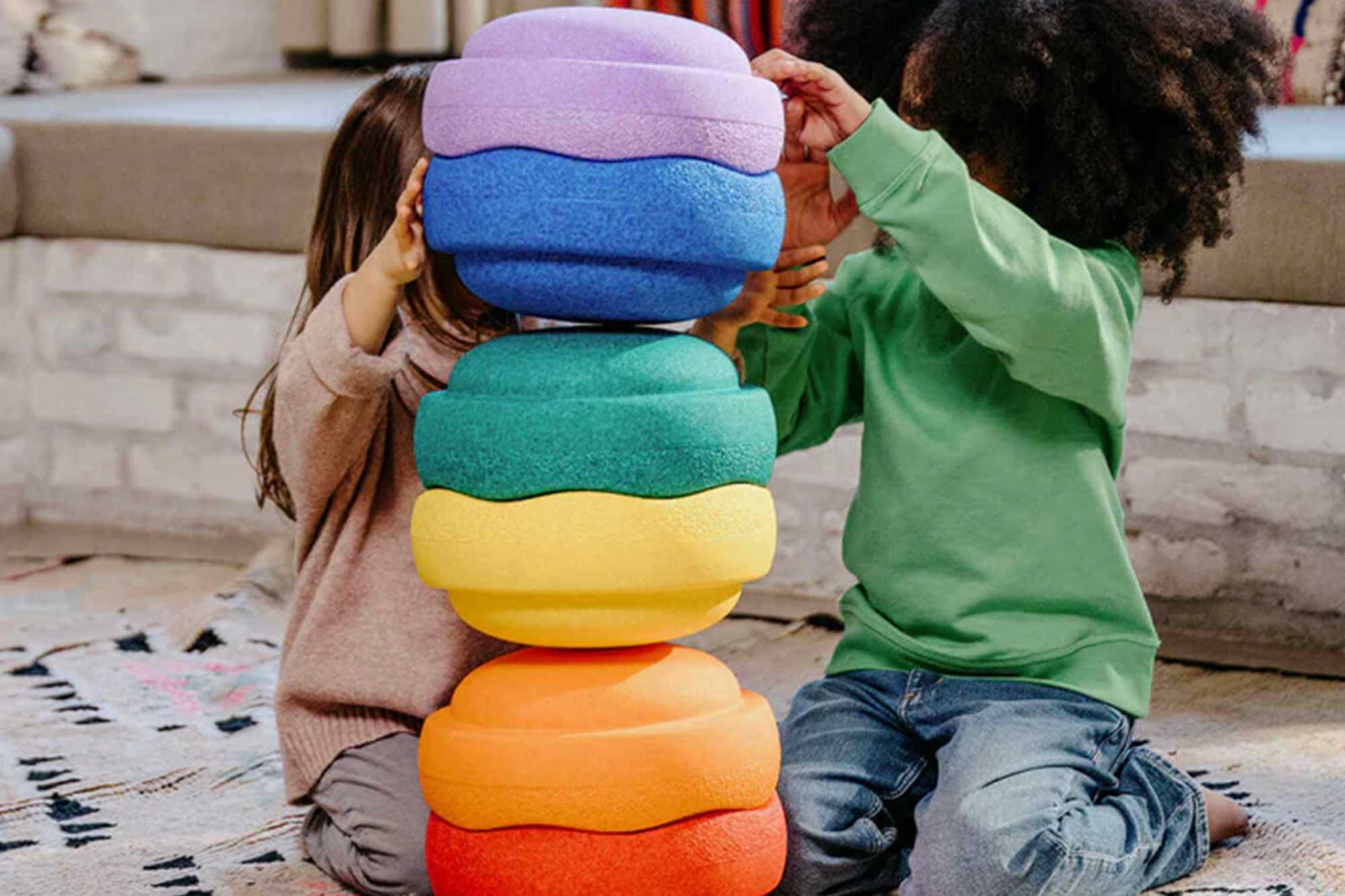 gestapelte bunte Stapelsteine mit zwei Kindern daneben