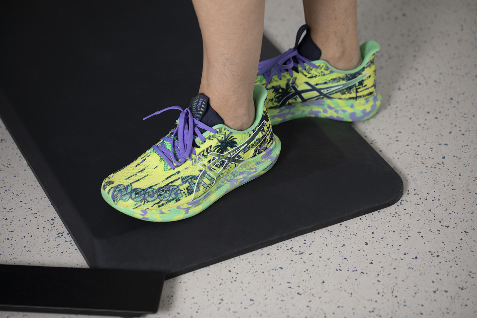 Füße mit Sportschuhen stehen auf einer ergonomischen Stehmatte