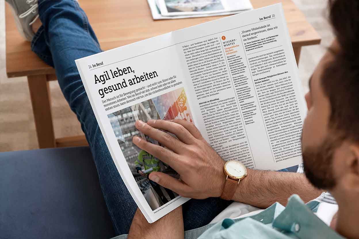 Mann sitzt entspannt und liest eine Zeitschrift mit Artikel über gesundes Arbeiten und Rückengesundheit im Alltag