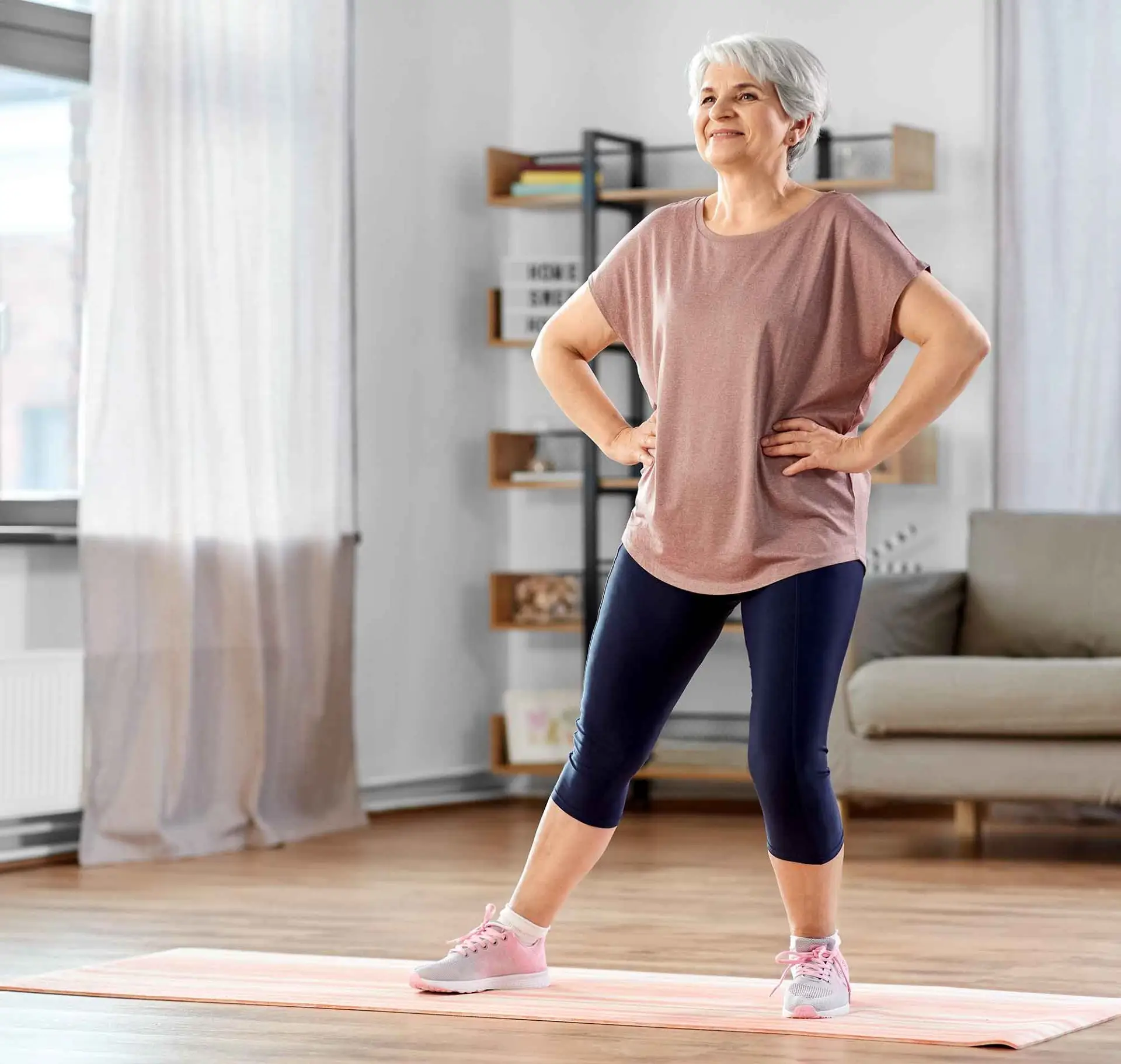 Eine Frau macht leichten Sport im Wohnzimmer.
