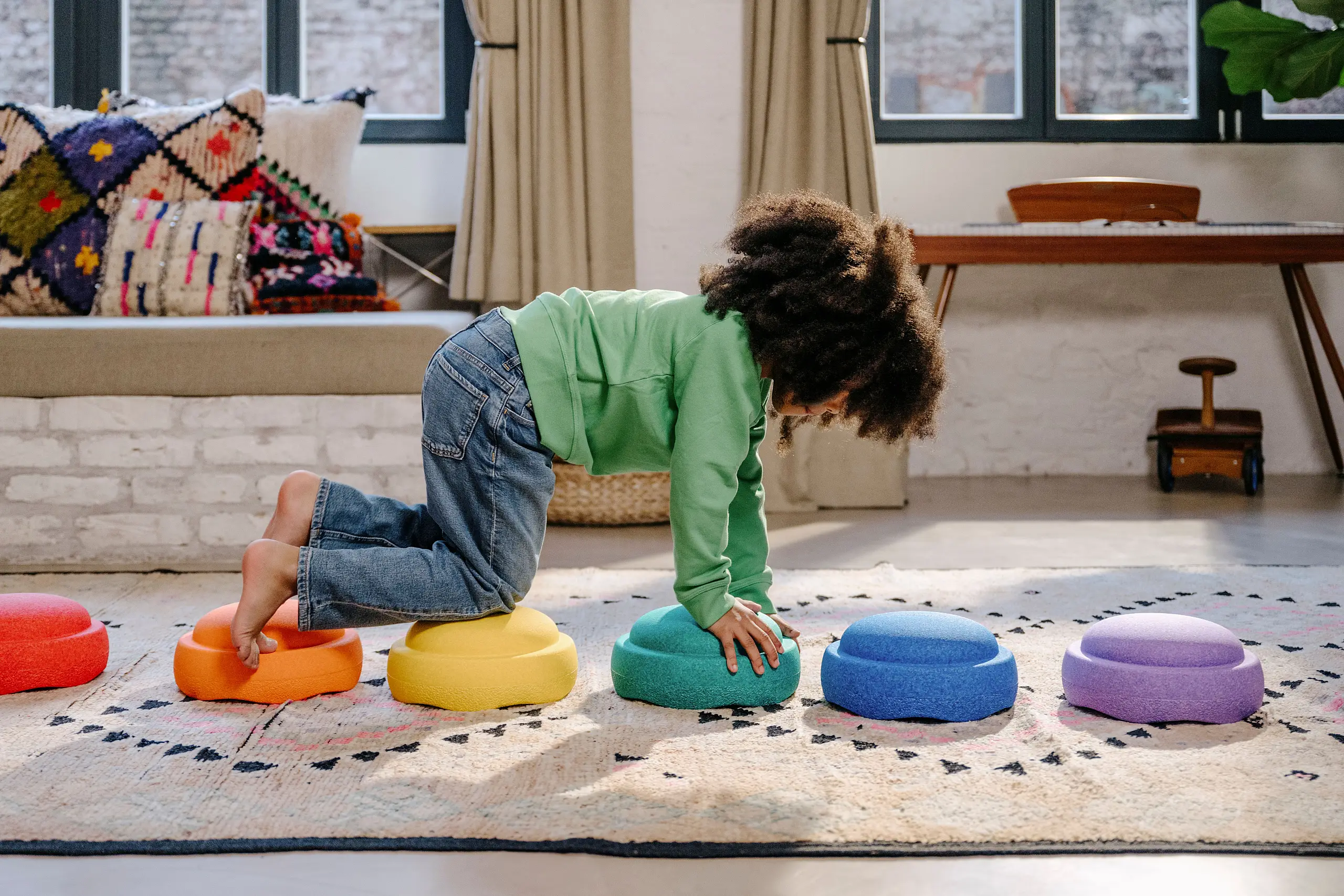 Ein Kind klettert über bunte Stapelsteine
